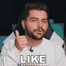 a man with a beard is giving a thumbs up and the word like is on the front of his shirt