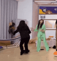 a woman in a green suit is dancing in front of a sign that says ' jee ' on it