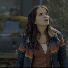a woman is wearing a blue and red jacket and a red sweater .