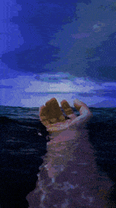 a person 's hand is reaching out into the ocean