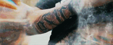 a close up of a person 's arm with a tattoo on it and a painting in the background .