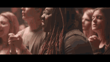 a woman with dreadlocks is sitting in a crowd