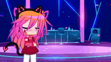 a cartoon girl with pink hair and cat ears is standing in a room with a speaker .
