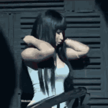 a woman with long black hair is standing in front of a wall .