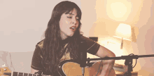 a woman playing a guitar in front of a microphone