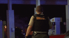 a sheriff stands in front of a gas station at night
