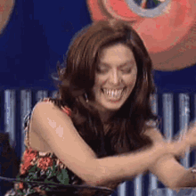 a woman is laughing while sitting at a table with her arms outstretched .
