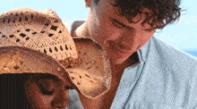 a man wearing a cowboy hat looks at a woman with her eyes closed