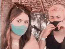 a man and a woman wearing masks are standing next to each other .