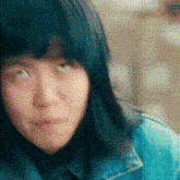 a close up of a woman 's face with a blue jacket on looking at the camera .