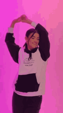 a woman is making a heart shape with her hands while wearing a hoodie .