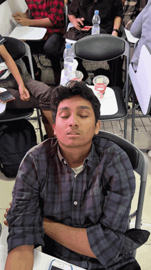a man in a plaid shirt is sleeping with his eyes closed