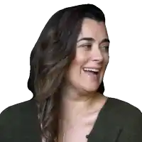 a woman wearing a green sweater is laughing with her mouth open
