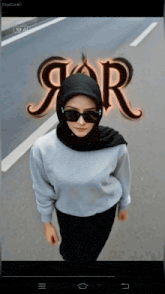 a woman wearing a hijab and sunglasses is standing in front of a sign that says j.r.