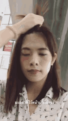 a woman in a white shirt is holding her hair in a bun