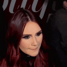 a woman with red hair is making a funny face in front of a sign that says muy
