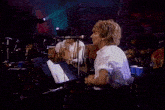 a man singing into a microphone while wearing a white shirt