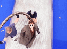 a man in a suit and sunglasses is being held by a snake