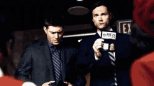 a man in a suit and tie is standing next to another man in a suit and tie .