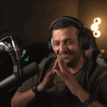 a man wearing headphones is sitting in front of a microphone and smiling