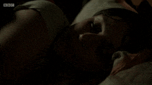 a woman laying on a bed with bbc written on the bottom of the screen