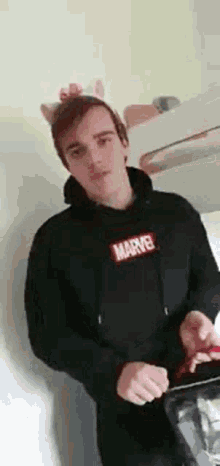 a man wearing a hoodie and a headband with cat ears is standing in a kitchen .