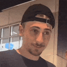 a man wearing a black baseball cap and a black shirt is smiling .