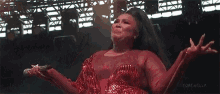 a woman in a red dress is singing into a microphone with coachella written on the bottom right