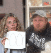 a man wearing a dallas cowboys sweatshirt holds up a sign