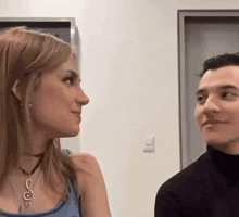 a man and a woman are looking at each other in a room and smiling .