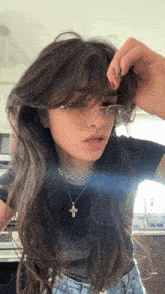 a woman wearing glasses and a cross necklace looks at the camera .