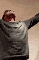 a man with his arms outstretched wearing sunglasses and a grey shirt