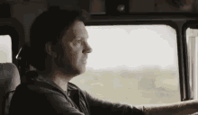 a man is sitting in the driver 's seat of a truck looking out the window .
