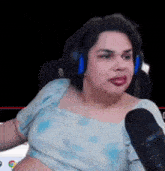 a woman is sitting in front of a microphone wearing headphones and a crop top .