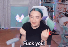 a woman with blue hair is sitting in a gaming chair and says fuck you