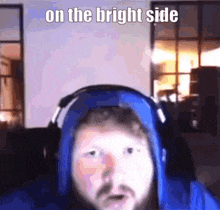 a man wearing headphones and a blue hoodie is standing in front of a window in a room .