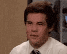 a man in a white shirt and tie is looking at the camera .