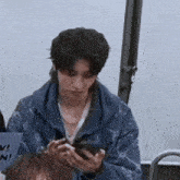 a man in a blue jacket is holding a cell phone .