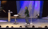 a man is dancing on stage in front of a microphone .