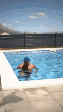 a man in a blue swim cap is swimming in a swimming pool
