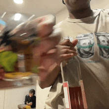 a man wearing a shirt that has a picture of a dollar bill on it is holding a bottle