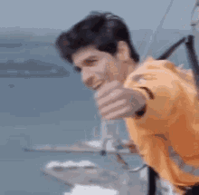 a man is giving a thumbs up while hanging from a rope .