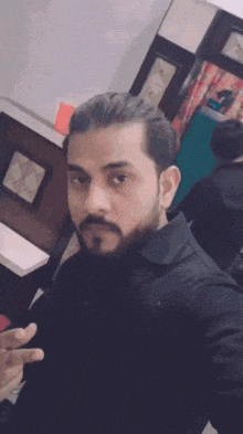 a man with a beard is taking a selfie in front of a mirror in a room .