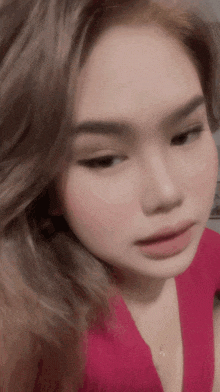 a close up of a woman 's face wearing a pink shirt