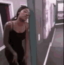 a woman in a black dress is leaning against a wall in a hallway .
