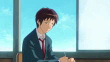 a man in a suit and tie sits in front of a window writing