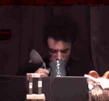 a man is holding a cup in front of his face with the letter n on it