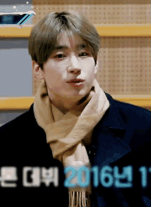 a young man wearing a scarf and a jacket with the year 2016 on the bottom right
