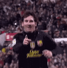 a soccer player is pointing at the camera while wearing a black shirt .