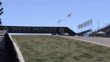 a sign that says west mirage is above a race track